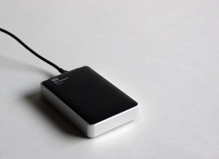 Photograph of portable hard drive on a greyish white backdrop.