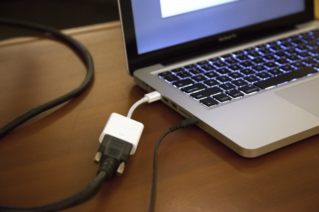 VGA cable connected to a laptop using a VGA to thunderbolt adapter.