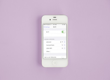 Photo of a white iPhone laying flat on a surface and showing iOS WiFi settings