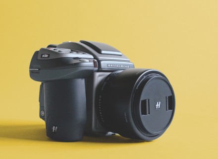 photo of a hasselblad digital camera with lens sitting on yellow backdrop.