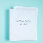 Image of Binder with piece of paper on it that says Media Cage Guide